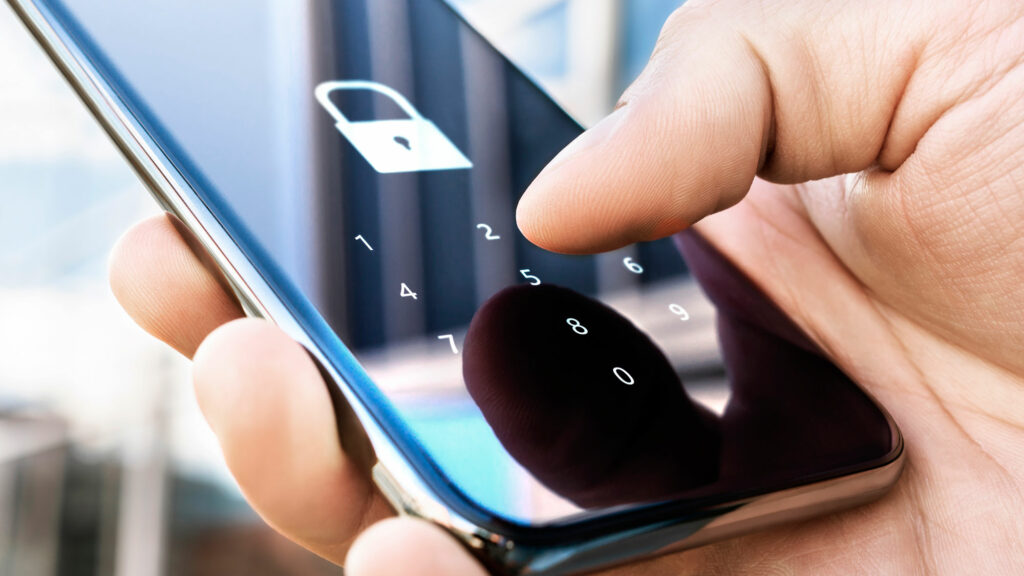Nærbilde av en hånd som taster inn kode på en telefon med hengelås-symbol, personen bruker totrinnsbekreftelse