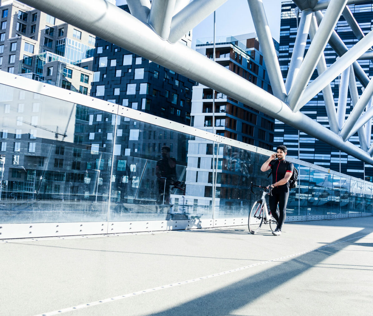 Mann triller sykkel over bru i Oslo mens han snakker i mobiltelefon