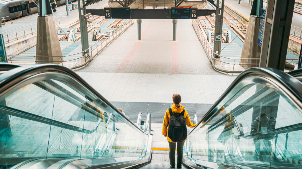Illustrasjon av en person på vei ned en rulletrapp på togstasjonen på vei til ferie.
