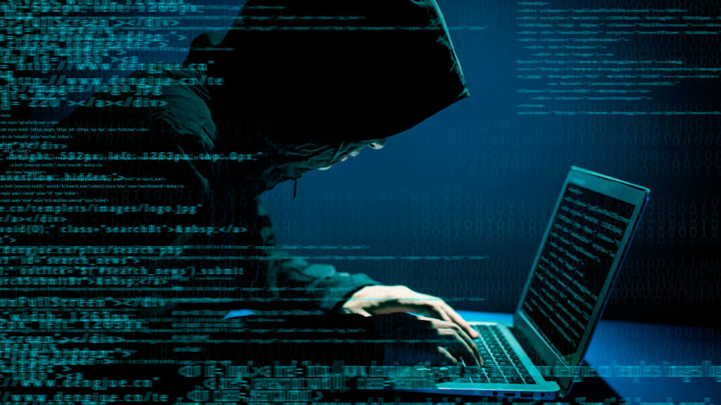 hacker sitter foran en data med koder og driver med ID-tyveri